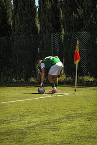 a man bending down to pick up a soccer ball