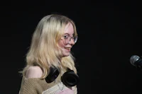 a girl with glasses and headphones standing in front of a microphone
