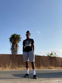 a man in black and white shorts standing on the side of the road