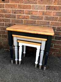 a set of three nesting tables in front of a brick wall