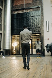 a man in a suit walking down a wooden floor