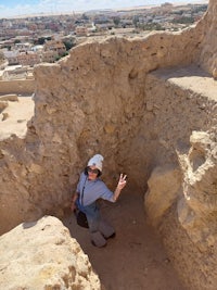 a woman in a hat is standing in a sand pit