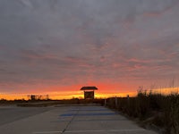 a sunset over a parking lot with a clock tower in the background