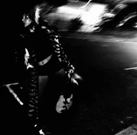 a black and white photo of a woman walking at night