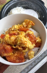 a person is holding a bowl of rice and a bowl of food