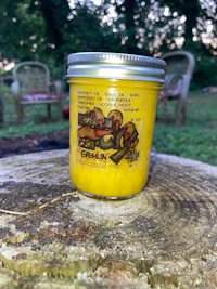a jar of yellow candle sitting on a stump