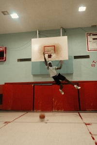 a man dunks a basketball in a gym