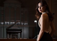 a woman in a black dress posing in front of a piano