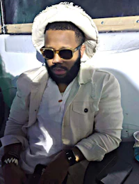 a man with a beard and sunglasses sitting on a bus