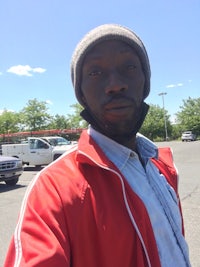 a man in a red jacket is taking a selfie in a parking lot