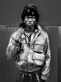 a black and white photo of a man in a jacket and jeans