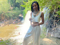 a woman is standing in front of a waterfall