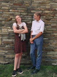 a man and a woman standing in front of a stone wall