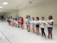 a group of children are standing in a dance studio