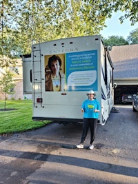 a woman standing in front of an rv with a sign on it