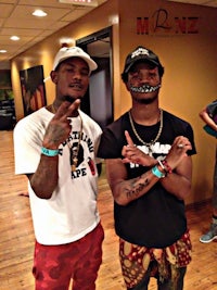 two men standing next to each other with tattoos on their faces