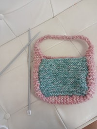 a knitted bag with knitting needles next to it