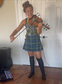 a woman in a kilt playing the violin