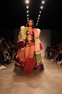 a model walks down the runway in a colorful outfit