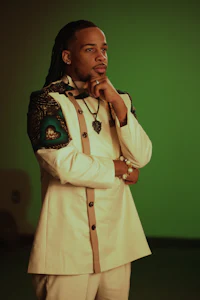 a man with dreadlocks standing in front of a green screen