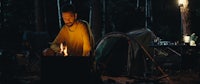 a man is cooking on a campfire in the woods