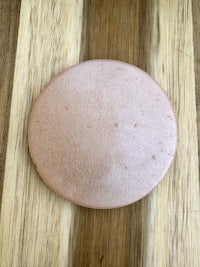 a piece of pink clay sitting on a wooden cutting board