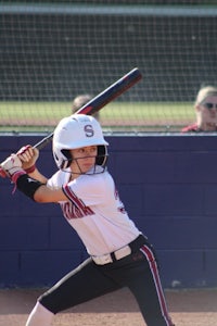 a softball player swinging a bat during a game
