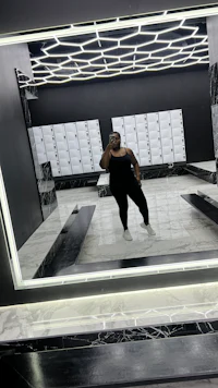 a woman standing in front of a mirror in a gym