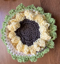 a crocheted sunflower dishcloth on a wooden table