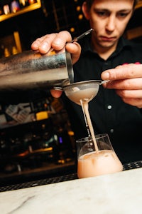 a bartender pouring a drink into a glass