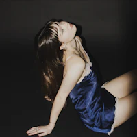 a woman in a blue dress laying on the ground