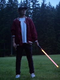 a man standing in a field holding a light saber