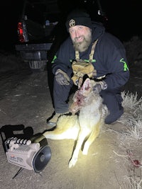 a man kneeling down next to a dead coyote