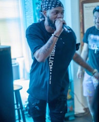 a man in a bandana is singing into a microphone