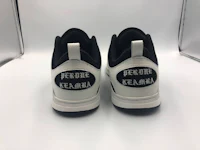 a pair of white and black sneakers with a black logo on them