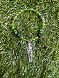 a green beaded bracelet is sitting on grass