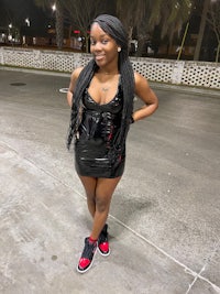 a black woman wearing a black dress and red sneakers