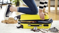 a woman sitting on top of a yellow suitcase