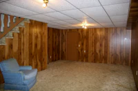 a basement with wood paneling and a chair