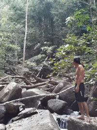 a man standing next to a stream in the jungle