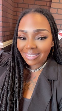 a black woman with dreadlocks smiling at the camera