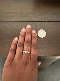 a woman's hand holding a coin next to a ring