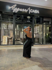 a woman in a black dress standing in front of a store