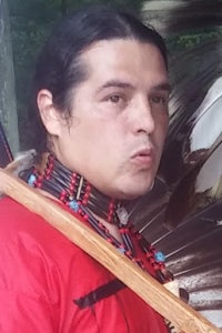 a man in a native outfit holding a bow and arrow