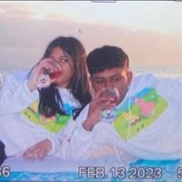 two people sitting on a beach with drinks in their hands