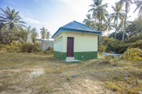 an outhouse in the middle of a field with palm trees