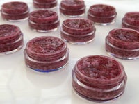 a group of small jars filled with raspberry lip balm