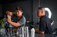 two men standing at a bar making drinks