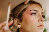 a woman is getting her makeup done by a makeup artist