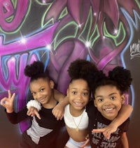 three girls posing in front of a graffiti wall